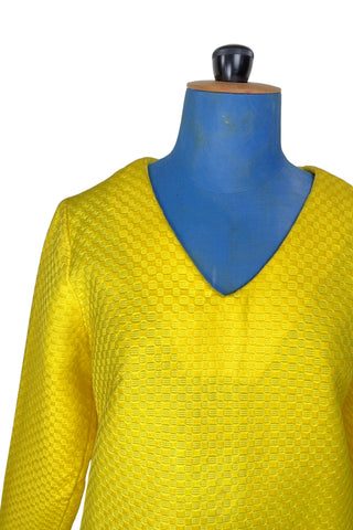 Vintage 1960s mod mini dress in bright yellow textured heavyweight cotton. The textured weave has a small circular motif that resembles bubbles. The dress features a V neckline, long sleeves, and closes in the back with a metal zipper.