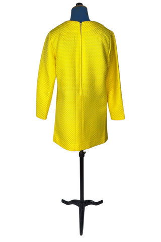 Vintage 1960s mod mini dress in bright yellow textured heavyweight cotton. The textured weave has a small circular motif that resembles bubbles. The dress features a V neckline, long sleeves, and closes in the back with a metal zipper.