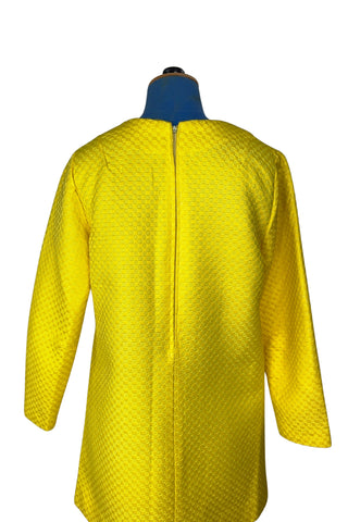 Vintage 1960s mod mini dress in bright yellow textured heavyweight cotton. The textured weave has a small circular motif that resembles bubbles. The dress features a V neckline, long sleeves, and closes in the back with a metal zipper.