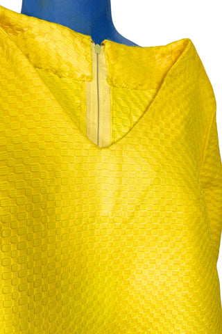 Vintage 1960s mod mini dress in bright yellow textured heavyweight cotton. The textured weave has a small circular motif that resembles bubbles. The dress features a V neckline, long sleeves, and closes in the back with a metal zipper.