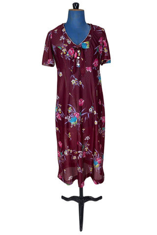 Vintage 1970s dress in burgundy red with a tulip and dianthus floral print. Features short flutter sleeves and a round neckline that can be gathered with the bow tie. The bodice closes with three white diamond shaped plastic buttons. The neckline and sleeves are finished with tiny white scalloped eyelet trim.