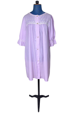 Vintage 1960s housecoat in lilac purple cotton blend with delicate white eyelet lace detail across the bust, and trimming the three-quarter length sleeves. The sleeves have gathered ruffle cuffs. The round neckline is trimmed with a tiny white lace ruffle. 

Designed by Adorable Lingerie. Marked size Medium.