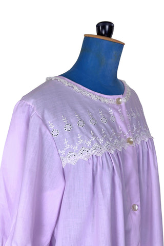 Vintage 1960s housecoat in lilac purple cotton blend with delicate white eyelet lace detail across the bust, and trimming the three-quarter length sleeves. The sleeves have gathered ruffle cuffs. The round neckline is trimmed with a tiny white lace ruffle. 

Designed by Adorable Lingerie. Marked size Medium.