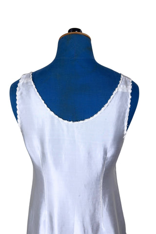 Vintage 1940s nightgown or slip, with cutwork embroidery across the bust, a pointed midriff yoke with vertical bust darts, and scalloped edging around the wide round neckline and hem. The hem has a small kick slit at the left, accented with floral appliqué and embroidery.