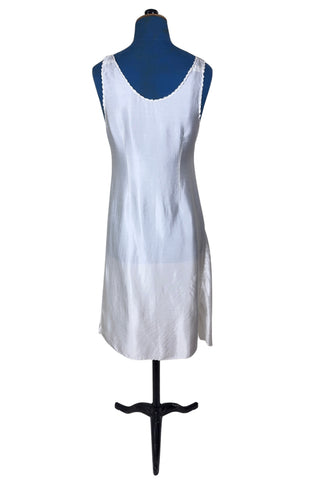 Vintage 1940s nightgown or slip, with cutwork embroidery across the bust, a pointed midriff yoke with vertical bust darts, and scalloped edging around the wide round neckline and hem. The hem has a small kick slit at the left, accented with floral appliqué and embroidery.