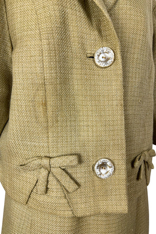 Vintage 1960s skirt suit with oversized jacket and matching skirt. The jacket features three-quarter length sleeves, bow accents at the waist, and closes with two large textured lucite buttons. The skirt has a pleat panel in the front, and closes in the back with a metal zipper.

The jacket and skirt are both lined in caramel brown rayon.

The jacket has a few light stains on the front, which would likely be removed with dry cleaning.