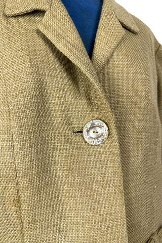 Vintage 1960s skirt suit with oversized jacket and matching skirt. The jacket features three-quarter length sleeves, bow accents at the waist, and closes with two large textured lucite buttons. The skirt has a pleat panel in the front, and closes in the back with a metal zipper.

The jacket and skirt are both lined in caramel brown rayon.

The jacket has a few light stains on the front, which would likely be removed with dry cleaning.