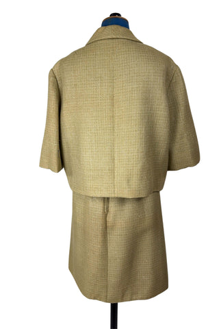 Vintage 1960s skirt suit with oversized jacket and matching skirt. The jacket features three-quarter length sleeves, bow accents at the waist, and closes with two large textured lucite buttons. The skirt has a pleat panel in the front, and closes in the back with a metal zipper.

The jacket and skirt are both lined in caramel brown rayon.

The jacket has a few light stains on the front, which would likely be removed with dry cleaning.