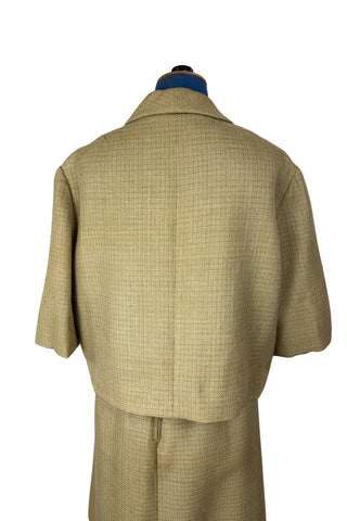 Vintage 1960s skirt suit with oversized jacket and matching skirt. The jacket features three-quarter length sleeves, bow accents at the waist, and closes with two large textured lucite buttons. The skirt has a pleat panel in the front, and closes in the back with a metal zipper.

The jacket and skirt are both lined in caramel brown rayon.

The jacket has a few light stains on the front, which would likely be removed with dry cleaning.