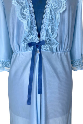 Vintage 1970s negligee robe in sky blue with wide lace trim along the deep V neckline and three-quarter length sleeve cuffs. Finished with a decorative royal blue bow. Closes at the waist with a single button.