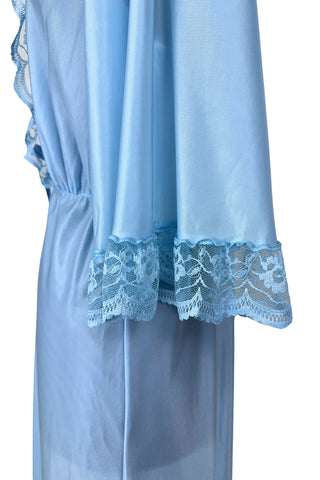 Vintage 1970s negligee robe in sky blue with wide lace trim along the deep V neckline and three-quarter length sleeve cuffs. Finished with a decorative royal blue bow. Closes at the waist with a single button.