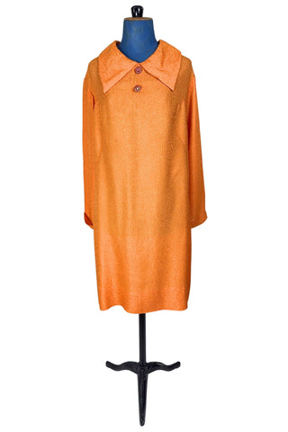 Vintage 1960s orange textured mod dress with long sleeves, large pointed collar, and two decorative rhinestone buttons. The long sleeves have turned cuffs. The A-line dress has bust darts through the sides and diagonally down towards the hips. Closes in the back with a cotton twill zipper.