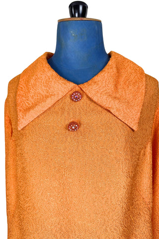Vintage 1960s orange textured mod dress with long sleeves, large pointed collar, and two decorative rhinestone buttons. The long sleeves have turned cuffs. The A-line dress has bust darts through the sides and diagonally down towards the hips. Closes in the back with a cotton twill zipper.