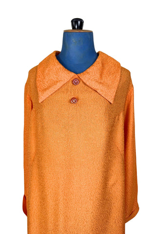 Vintage 1960s orange textured mod dress with long sleeves, large pointed collar, and two decorative rhinestone buttons. The long sleeves have turned cuffs. The A-line dress has bust darts through the sides and diagonally down towards the hips. Closes in the back with a cotton twill zipper.