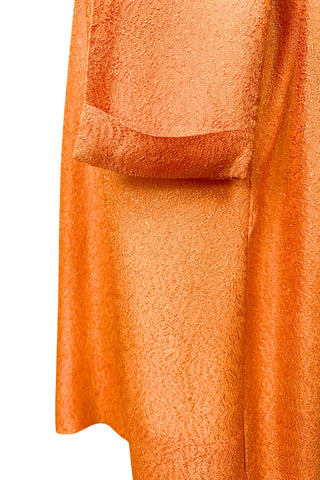 Vintage 1960s orange textured mod dress with long sleeves, large pointed collar, and two decorative rhinestone buttons. The long sleeves have turned cuffs. The A-line dress has bust darts through the sides and diagonally down towards the hips. Closes in the back with a cotton twill zipper.