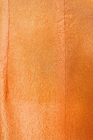 Vintage 1960s orange textured mod dress with long sleeves, large pointed collar, and two decorative rhinestone buttons. The long sleeves have turned cuffs. The A-line dress has bust darts through the sides and diagonally down towards the hips. Closes in the back with a cotton twill zipper.