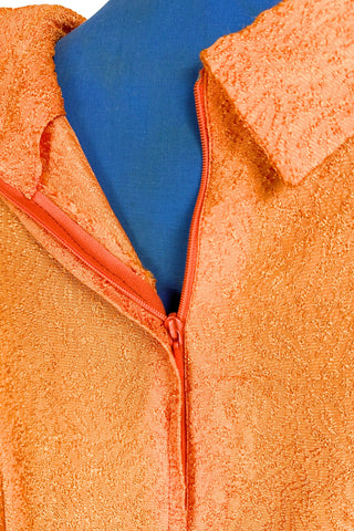 Vintage 1960s orange textured mod dress with long sleeves, large pointed collar, and two decorative rhinestone buttons. The long sleeves have turned cuffs. The A-line dress has bust darts through the sides and diagonally down towards the hips. Closes in the back with a cotton twill zipper.