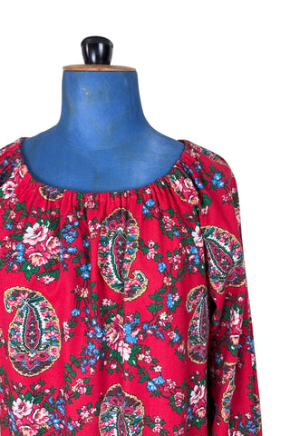 Vintage 1970s bohemian dress with paisley print on a rich red background. The dress is made from cotton, and  features a round, elasticized neckline and long sleeves with elasticized cuffs. There are no closures, it is a pullover style.
