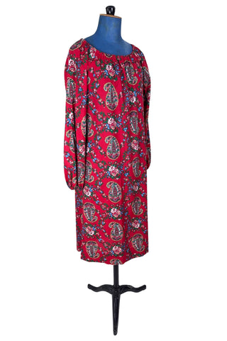 Vintage 1970s bohemian dress with paisley print on a rich red background. The dress is made from cotton, and  features a round, elasticized neckline and long sleeves with elasticized cuffs. There are no closures, it is a pullover style.