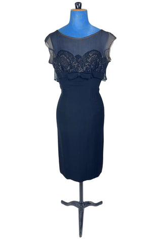 Vintage 1950s black chiffon cocktail dress with strapless lace bodice with chiffon overlay, finished with a empire waist sash with bow. The top of the bodice has a light beige chiffon layer creating a nude illusion, with a floating outer layer of black chiffon that continues in the back as a waist-length cape. A tiny bow perfectly sets off the back of the collar. 

The dress closes in the back with a metal zipper, and is fully lined. 

In excellent vintage condition, with minor wear to the chiffon near...
