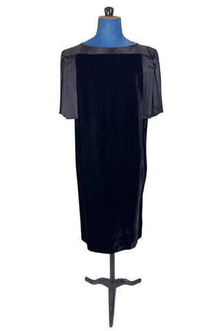 Vintage 1980s cocktail dress in black velvet with pleated black satin sleeves. The dress has a straight column silhouette. The back features a deep V pleated satin panel and satin strap across the back with small buttons at the back of the collar. The dress has no zipper or other closure.

Designed by Lady Kate. Union made in U.S.A. by ILGWU / AFL CIO. Marked Size 8 Petite.