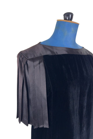 Vintage 1980s cocktail dress in black velvet with pleated black satin sleeves. The dress has a straight column silhouette. The back features a deep V pleated satin panel and satin strap across the back with small buttons at the back of the collar. The dress has no zipper or other closure.

Designed by Lady Kate. Union made in U.S.A. by ILGWU / AFL CIO. Marked Size 8 Petite.