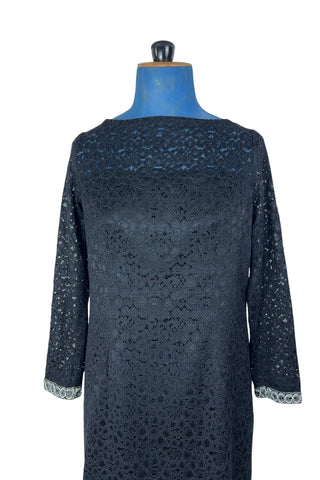 Vintage 1960s cocktail dress in black corded lace with see-through upper bodice and sleeves. The long sleeves are embellished with silver corded soutache trim. The dress closes in the back with a cotton twill zipper, and is fully lined.