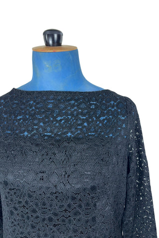 Vintage 1960s cocktail dress in black corded lace with see-through upper bodice and sleeves. The long sleeves are embellished with silver corded soutache trim. The dress closes in the back with a cotton twill zipper, and is fully lined.