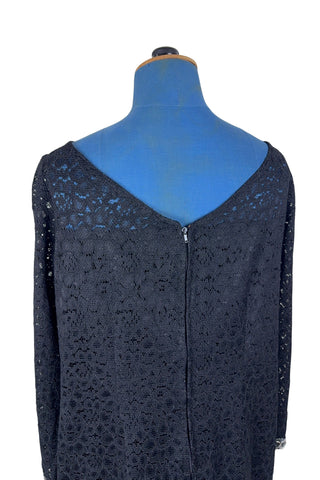 Vintage 1960s cocktail dress in black corded lace with see-through upper bodice and sleeves. The long sleeves are embellished with silver corded soutache trim. The dress closes in the back with a cotton twill zipper, and is fully lined.