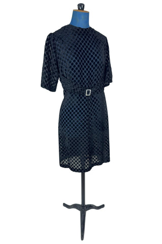 Vintage 1960s sheer black dress with flocked polkadot design. This sweet little black dress features short sleeves, and an integrated sash belt across the front with a rhinestone buckle belt. The dress closes in the back with a cotton twill zipper and is unlined. 