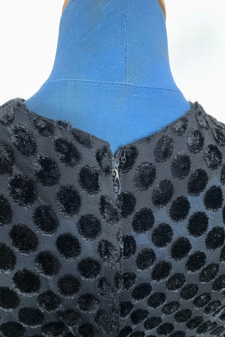 Vintage 1960s sheer black dress with flocked polkadot design. This sweet little black dress features short sleeves, and an integrated sash belt across the front with a rhinestone buckle belt. The dress closes in the back with a cotton twill zipper and is unlined. 