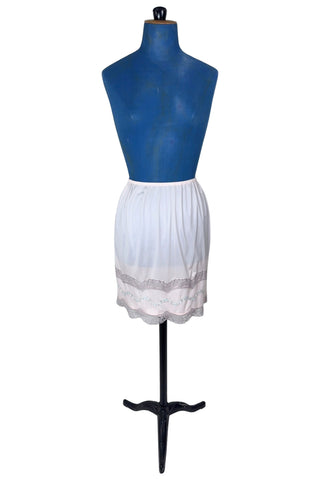 Vintage 1950s Kayser half slip in light pink with grey scalloped lace trim. The bottom of the slip is decorated with a wide panel of overlay chiffon embroidered with a floral chain. The waist is elasticized.

Designed by Kayser. Made in Canada. Marked size Small / Short.