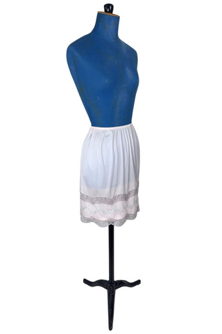 Vintage 1950s Kayser half slip in light pink with grey scalloped lace trim. The bottom of the slip is decorated with a wide panel of overlay chiffon embroidered with a floral chain. The waist is elasticized.

Designed by Kayser. Made in Canada. Marked size Small / Short.
