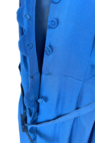 Vintage 1940s day dress in royal blue rayon with scalloped collar and front button placket, which closes with 14 functional self-fabric buttons down the front. The dress has three quarter sleeves with folded cuffs, and a matching self-fabric belt with a rectangular covered buckle. 
Condition Note: The dress is in very good vintage condition, with an inconspicuous small darkened area on the lower back of the skirt about 1-2” long.
