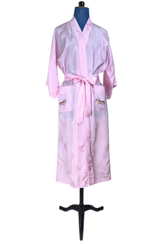 Vintage 1960s kimono style robe in light pink rayon damask, with embroidered crane birds and nature scenes. Features a deep V neckline, three-quarter length wide sleeves, and two large pockets decorated with embroidery. The back of the robe has a large embroidered motif.