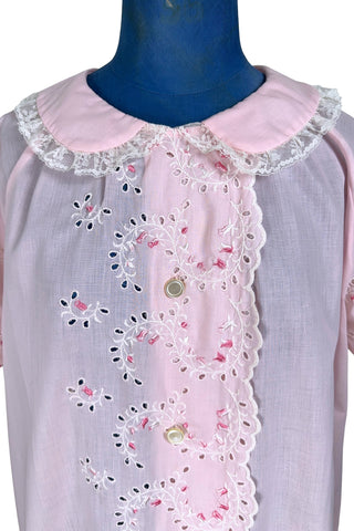 Vintage late 1950s robe in light pink with large scalloped eyelet embroidery down the front and around the short sleeves. The peignoir style robe features short sleeves with matching openwork floral embroidery, and a Peter Pan collar trimmed with dainty white lace. The robe closes with five flat ivory pearl buttons, and a hidden snap under the collar.

A Perri-Ann design by Faris. Made in Canada.