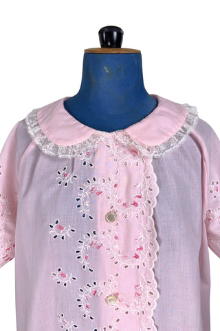 Vintage late 1950s robe in light pink with large scalloped eyelet embroidery down the front and around the short sleeves. The peignoir style robe features short sleeves with matching openwork floral embroidery, and a Peter Pan collar trimmed with dainty white lace. The robe closes with five flat ivory pearl buttons, and a hidden snap under the collar.

A Perri-Ann design by Faris. Made in Canada.