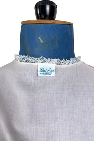 Vintage late 1950s pajama top shirt in light pink cotton with wide panels of eyelet embroidery down the front and at the sleeve cuffs. The high collar, sleeves, and hem are finished with tiny white ruffled lace.

Designed by Perri-Ann Lingerie in Montreal, Canada.