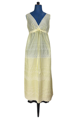 Vintage 1960s nightgown in yellow cotton with white eyelet embroidery. The nightgown is sleeveless, with a deep V neckline and gathered empire waist which ties with a yellow ribbon woven through eyelet lace trim. The back of the nightgown has a similar deep V cut.