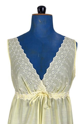 Vintage 1960s nightgown in yellow cotton with white eyelet embroidery. The nightgown is sleeveless, with a deep V neckline and gathered empire waist which ties with a yellow ribbon woven through eyelet lace trim. The back of the nightgown has a similar deep V cut.
