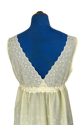 Vintage 1960s nightgown in yellow cotton with white eyelet embroidery. The nightgown is sleeveless, with a deep V neckline and gathered empire waist which ties with a yellow ribbon woven through eyelet lace trim. The back of the nightgown has a similar deep V cut.