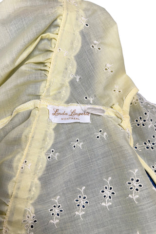Vintage 1960s nightgown in yellow cotton with white eyelet embroidery. The nightgown is sleeveless, with a deep V neckline and gathered empire waist which ties with a yellow ribbon woven through eyelet lace trim. The back of the nightgown has a similar deep V cut.