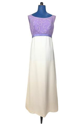 Gorgeous vintage 1960s evening gown with lilac purple bodice and creamy white long A-line skirt. The empire waist gown’s bodice features swirls of pearly white beading, and is finished with a wide purple satin sash at the waist with a large bow in the back.

The sleeveless dress has a wide round collar with a lower scoop back. It is fully lined, and closes in the back with a cotton twill nylon zipper.