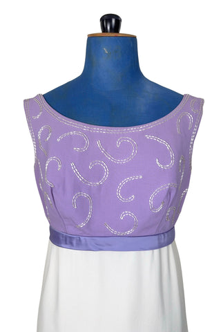 Gorgeous vintage 1960s evening gown with lilac purple bodice and creamy white long A-line skirt. The empire waist gown’s bodice features swirls of pearly white beading, and is finished with a wide purple satin sash at the waist with a large bow in the back.

The sleeveless dress has a wide round collar with a lower scoop back. It is fully lined, and closes in the back with a cotton twill nylon zipper.