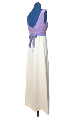 Gorgeous vintage 1960s evening gown with lilac purple bodice and creamy white long A-line skirt. The empire waist gown’s bodice features swirls of pearly white beading, and is finished with a wide purple satin sash at the waist with a large bow in the back.

The sleeveless dress has a wide round collar with a lower scoop back. It is fully lined, and closes in the back with a cotton twill nylon zipper.
