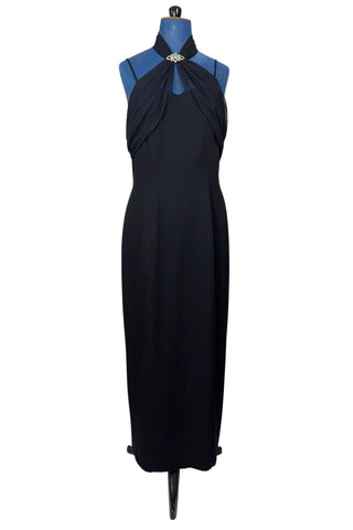 Vintage 1990s black evening gown with silver tone rhinestone brooch at the neck. This sophisticated dress has a column silhouette, and features a sweetheart neckline, spaghetti straps, and a slit at the back of the skirt. Sheer black chiffon is layered and draped at the neck in a halter style, and flows down the bodice to the back of the waist where it forms a floating overlay ruffle.

The dress is fully lined with black acetate, and closes in the back with a nylon zipper.

Marked Size 10. Made in U.S.A.