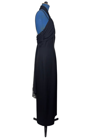 Vintage 1990s black evening gown with silver tone rhinestone brooch at the neck. This sophisticated dress has a column silhouette, and features a sweetheart neckline, spaghetti straps, and a slit at the back of the skirt. Sheer black chiffon is layered and draped at the neck in a halter style, and flows down the bodice to the back of the waist where it forms a floating overlay ruffle.

The dress is fully lined with black acetate, and closes in the back with a nylon zipper.

Marked Size 10. Made in U.S.A.