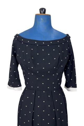 Unique true vintage 1950s “secretary” dress with detachable collar and cuffs for easy washing and ironing. The dress is made of black cotton (may have some linen content as well) with tiny white arc shaped embroidered polkadots. The collar and cuffs are made of crisp white linen/cotton, and attach with a series of metal snaps around the neckline and cuffs. The collar has a set of two bound buttonholes that a ribbon or scarf may be threaded through. The dress can be worn with any combination of collar,...