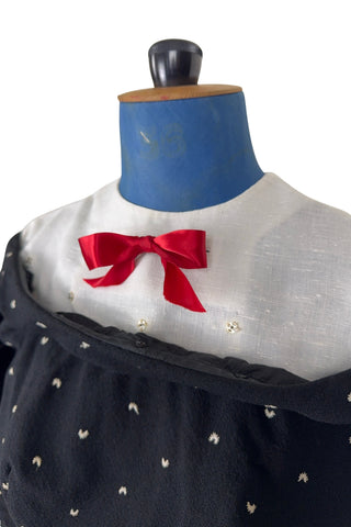 Unique true vintage 1950s “secretary” dress with detachable collar and cuffs for easy washing and ironing. The dress is made of black cotton (may have some linen content as well) with tiny white arc shaped embroidered polkadots. The collar and cuffs are made of crisp white linen/cotton, and attach with a series of metal snaps around the neckline and cuffs. The collar has a set of two bound buttonholes that a ribbon or scarf may be threaded through. The dress can be worn with any combination of collar,...