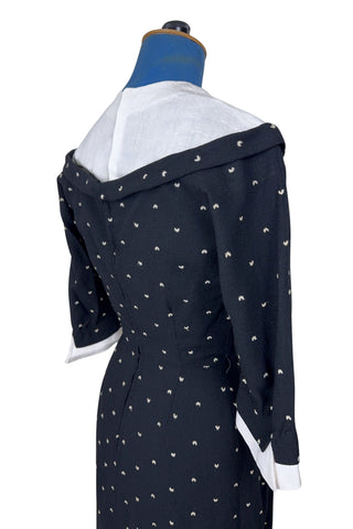 Unique true vintage 1950s “secretary” dress with detachable collar and cuffs for easy washing and ironing. The dress is made of black cotton (may have some linen content as well) with tiny white arc shaped embroidered polkadots. The collar and cuffs are made of crisp white linen/cotton, and attach with a series of metal snaps around the neckline and cuffs. The collar has a set of two bound buttonholes that a ribbon or scarf may be threaded through. The dress can be worn with any combination of collar,...